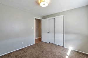 Unfurnished bedroom with a closet, carpet flooring, and a textured ceiling