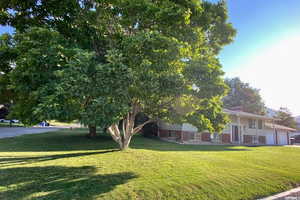 View of front facade featuring a front lawn, brick siding, and a garage