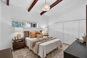 Primary Bedroom featuring vaulted ceiling with beams and an elegant statement chandelier. Complete with soft neutral carpeting, this bright and spacious bedroom is designed for relaxation.