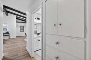 Hallway featuring abundant built-in linen storage for effortless organization. The seamless light-toned flooring continues the home's warm, modern feel.