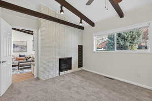 Flex-room featuring lofted beamed ceilings and a stately brick fireplace. Would make a great home office or music room with neutral carpeting, natural light and character.