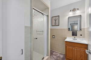 Bathroom featuring a glass-door shower with durable tile surrounds, classic tile wainscotting and built-in cabinetry above the commode.
