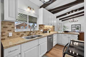 Kitchen featuring vaulted beams, crisp white cabinets, and stainless-accented range. Light wood-look floors and a stylish backsplash complete this space.