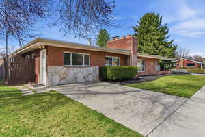 Classic ranch-style home, finished with a low-maintenance mix of timeless brick and natural stone siding. A stately chimney anchors the design, creating a sense of enduring quality and charm.