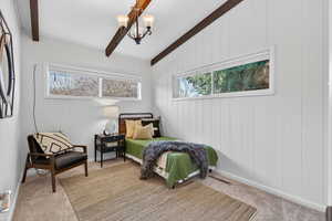 Bedroom #3 with soft neutral carpet flooring, multiple windows, vaulted ceiling with beams, and a chandelier.