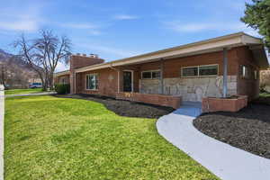 Classic curb appeal greets you at this residence, featuring natural stone accents and a welcoming no-step front porch. The expansive front lawn and prominent brick chimney create a timeless look.