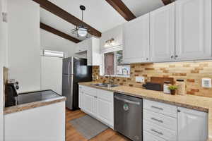 Enjoy backyard views from this kitchen featuring lofted beamed ceilings, stainless steel finishes and bright white cabinetry. Completed with seamless flooring and a tasteful backsplash, this space blends style and function.