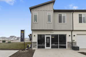 Rear view of property with stone siding, board and batten siding, an attached garage, and a lawn