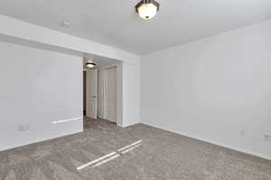 Carpeted spare room with baseboards and a textured ceiling