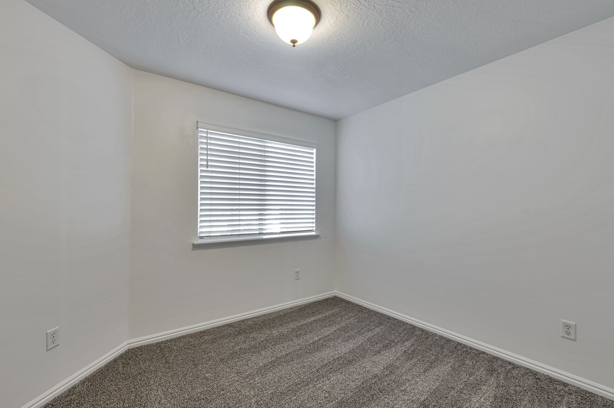 Spare room featuring dark colored carpet and a textured ceiling