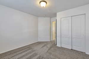Unfurnished bedroom with carpet flooring, a closet, and a textured ceiling