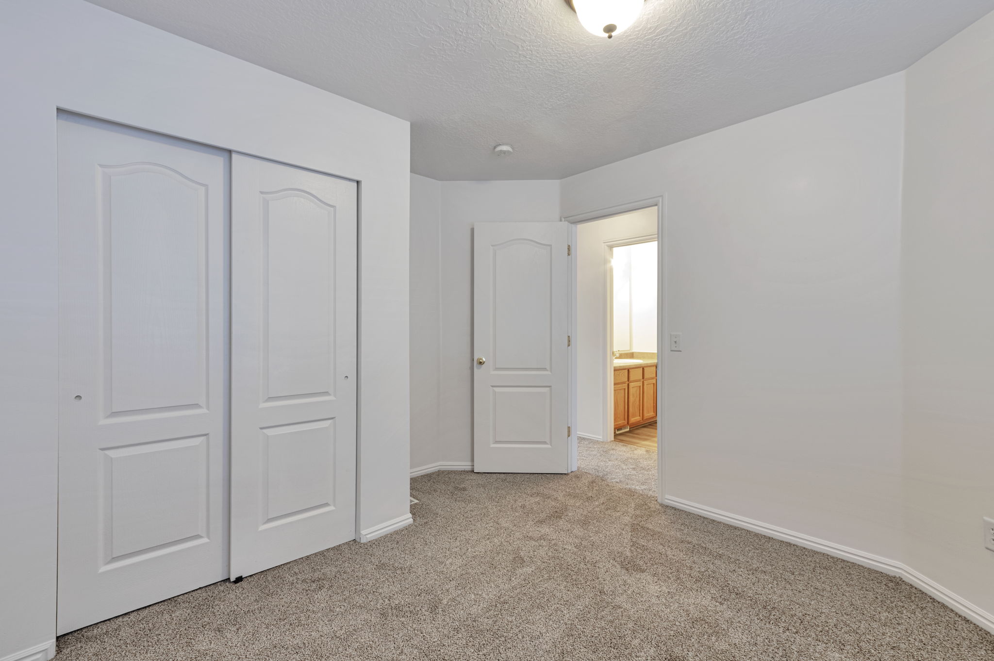 Unfurnished bedroom featuring light carpet, a closet, and a textured ceiling