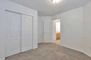 Unfurnished bedroom featuring light carpet, a closet, and a textured ceiling