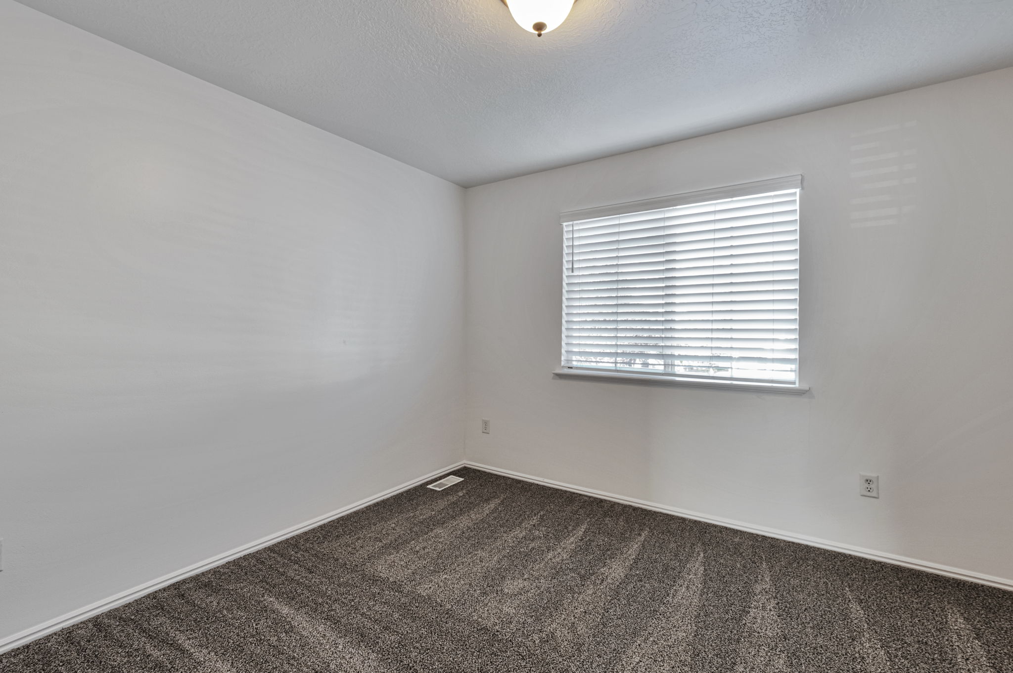 Spare room featuring dark colored carpet and a textured ceiling