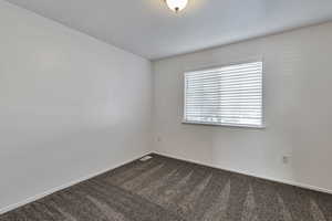 Spare room featuring dark colored carpet and a textured ceiling