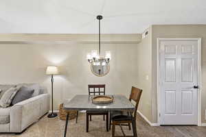 Carpeted dining room with baseboards and a chandelier