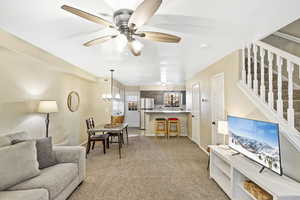 Living room with light colored carpet, a chandelier, and ceiling fan