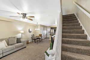 Stairway with carpet floors, a ceiling fan, and a chandelier