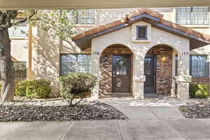 Property entrance with a tile roof, brick siding, and stucco siding