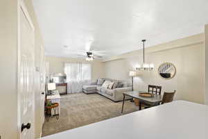 Living area featuring light colored carpet, ceiling fan, and hanging lights