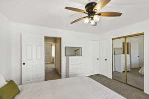 Bedroom featuring dark colored carpet, ceiling fan, and a closet