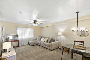 Living area with carpet flooring, hanging lights, and ceiling fan