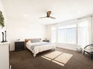 Primary bedroom with ceiling fan, carpet, large windows, and recessed lighting