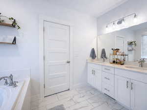 Primary ensuite bathroom with double vanity, a bath, and light marble finish flooring