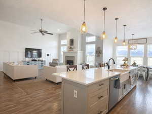 Kitchen with a large island with sink, light stone countertops, wood-type floors, stainless steel appliances, and multiple windows