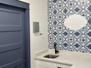 Laundry area featuring a pocket door, sink, and light stone countertops