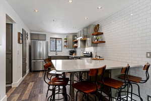 Kitchen featuring a kitchen bar, open shelves, gray cabinetry, a peninsula, and recessed lighting
