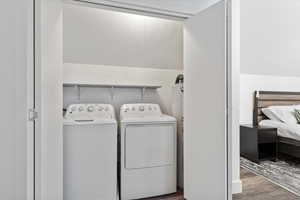 Laundry area with wood finished floors, washer and dryer, and electric water heater