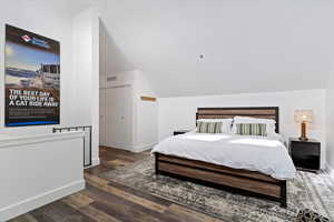 Bedroom featuring vaulted ceiling and dark wood-style flooring