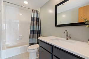 Bathroom with vanity, shower / tub combo, and light tile patterned flooring