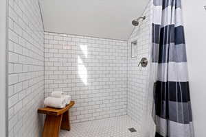 Bathroom featuring a shower stall, tile walls, and vaulted ceiling
