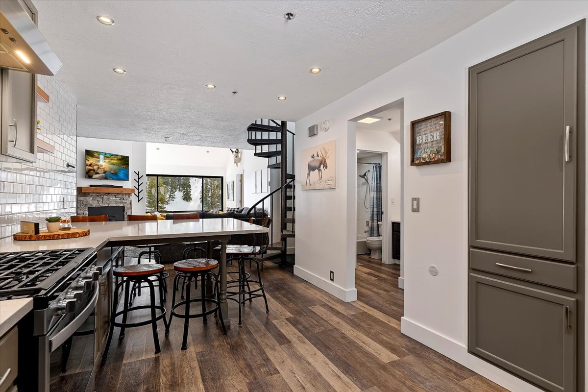 Kitchen featuring a peninsula, exhaust hood, a breakfast bar, dark wood-style flooring, and a fireplace