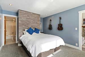 Carpeted bedroom with connected bathroom and baseboards