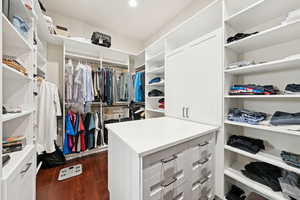 Walk in closet with dark wood-style flooring