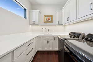 Laundry area featuring washer and dryer, dark wood-type flooring, and cabinet space