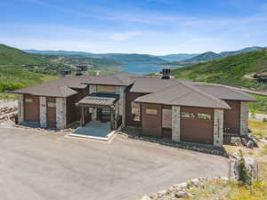 Prairie-style home featuring a mountain view, stone siding, a garage, and roof with shingles