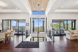 Living room featuring dark wood-type flooring, plenty of natural light, suspended lighting, and a wooden tray ceiling