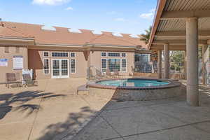 View of swimming pool with a community hot tub, patio surround, a swimming pool, and french doors