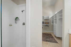 Full bath with a stall shower, a spacious closet, vanity, and light tile patterned flooring