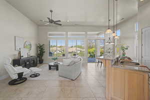 Living area with a high ceiling, a ceiling fan, light tile patterned floors, and recessed lighting