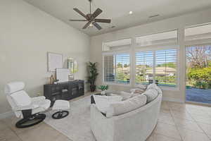 Living room featuring a ceiling fan, light tile patterned floors, recessed lighting, and a high ceiling