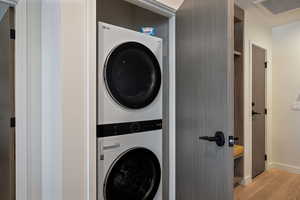 Laundry area featuring stacked washer / drying machine and light wood-type flooring
