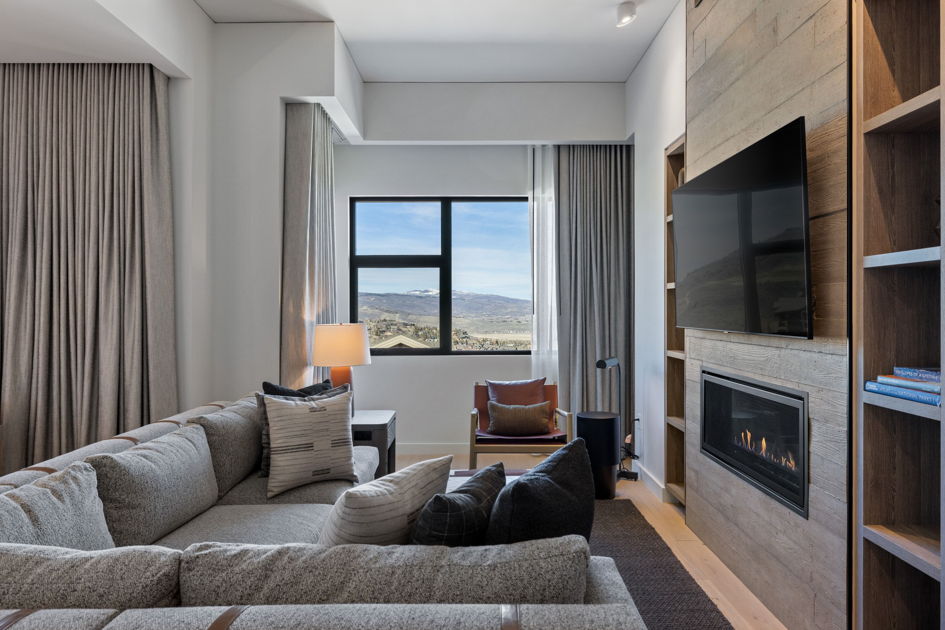 Living room featuring a large fireplace, light wood-style floors, and built in shelves