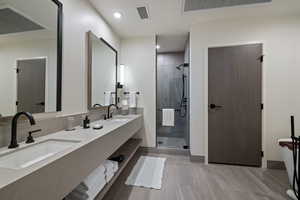 Bathroom featuring a shower stall, double vanity, recessed lighting, and a freestanding tub