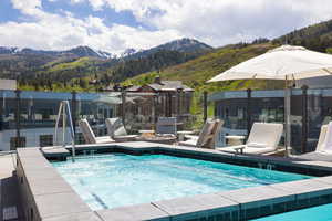 View of swimming pool with a mountain view, an outdoor fire pit, and patio surround