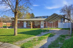 View of front of home featuring brick siding, driveway, and a detached carport